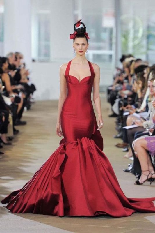 woman wears red gown on the runway at a fashion show