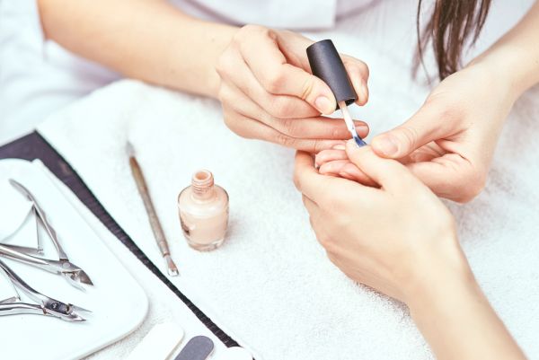Woman applying nail polish to a nail salon client