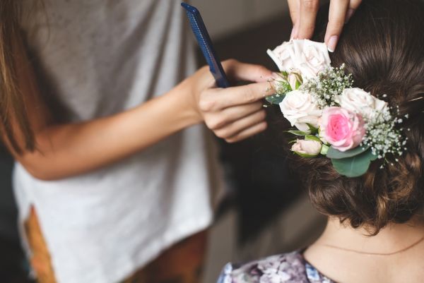 woman doing a bride's hair pinning flowers in place