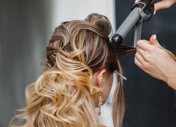 woman getting her hair styled with curling iron