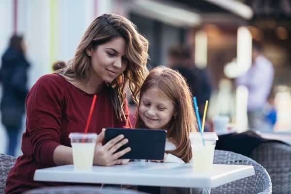 mother and daughter at a cafe look at tablet together