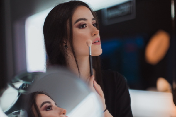 a beauty blogger puts on makeup in front of a mirror