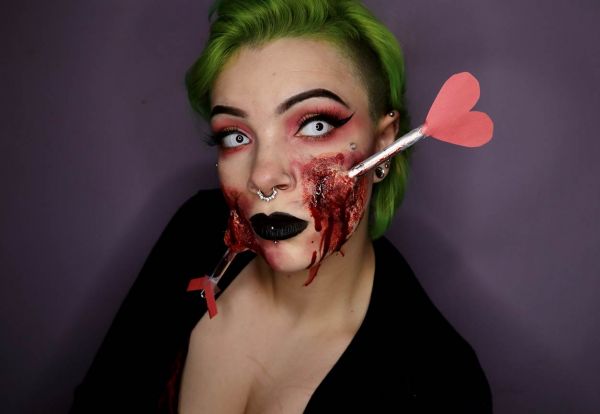 woman with green hair with special effects makeup showing an arrow going through her face