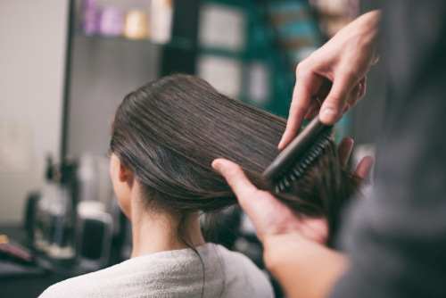 dark haired woman having her hair styled at salon